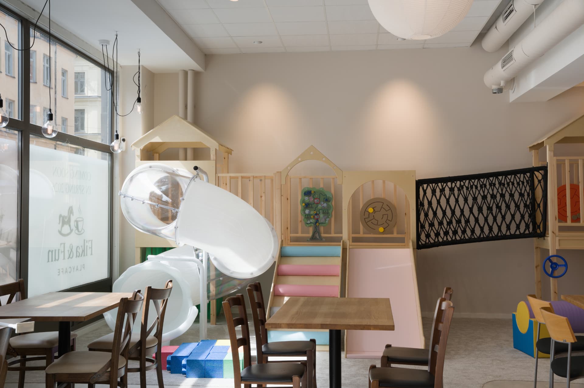 Cafédel med bord och stolar intill den vita tunnelrutschkanan