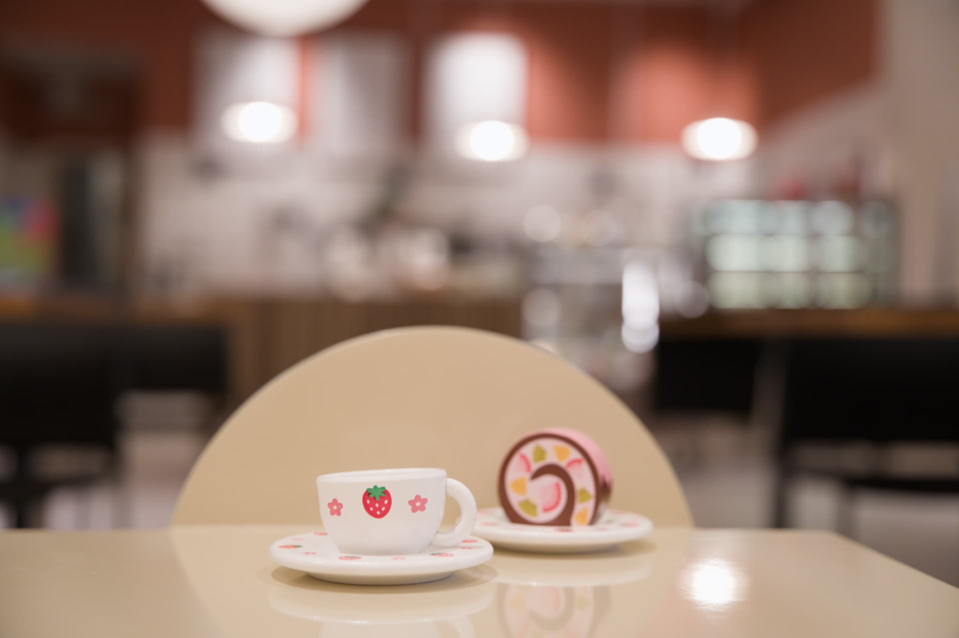 Leksakskopp och tårtbit på ett cafébord framför disken